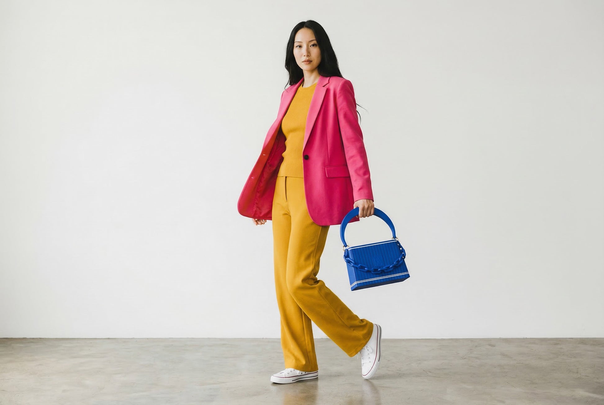 Model trägt HAKO Handtasche in Blau mit Ketten-Detail, moderner Lifestyle-Look im minimalistischen Studio