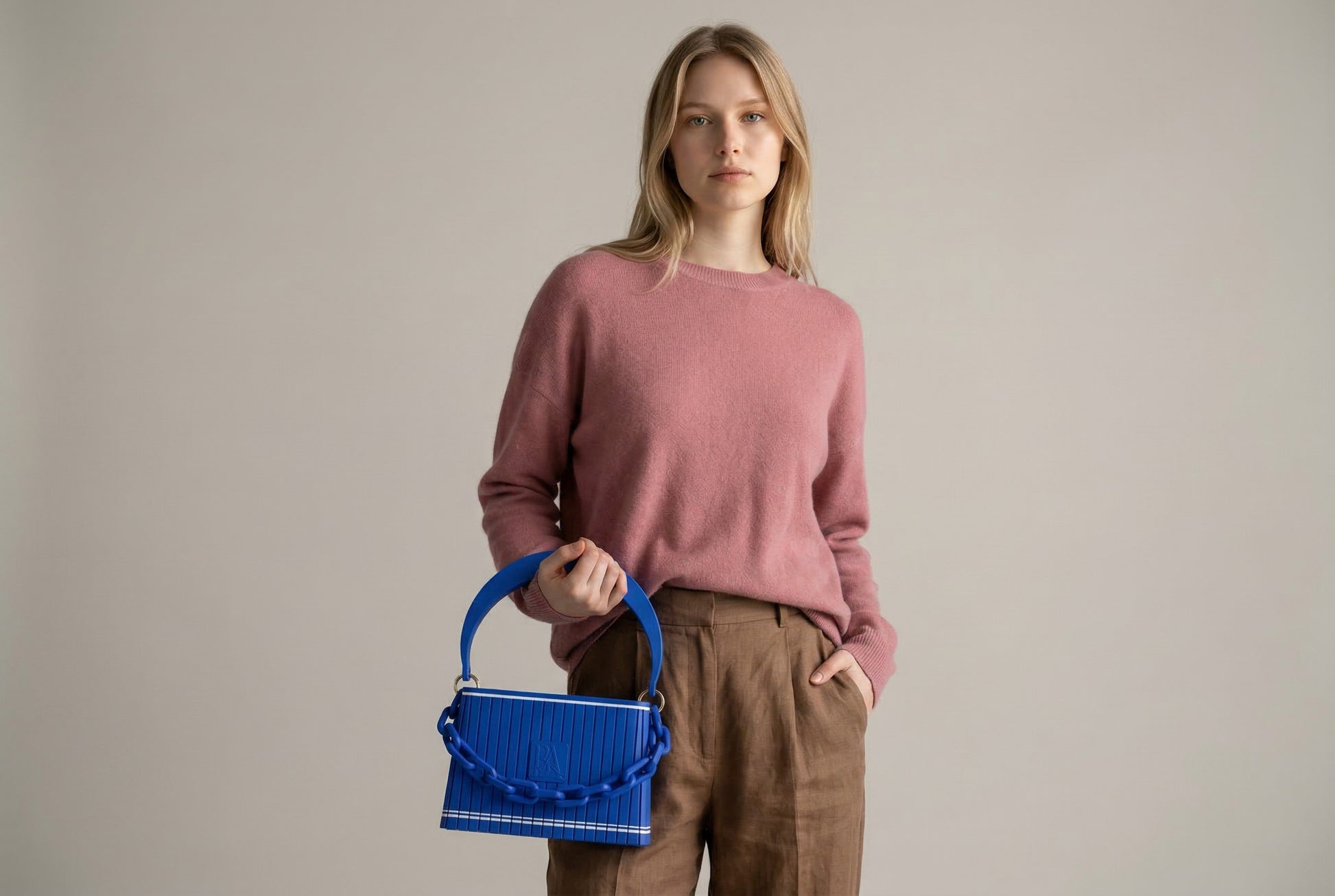 Model trägt HAKO Handtasche in Blau mit Ketten-Detail, minimalistischer Lifestyle-Look in neutralem Studio