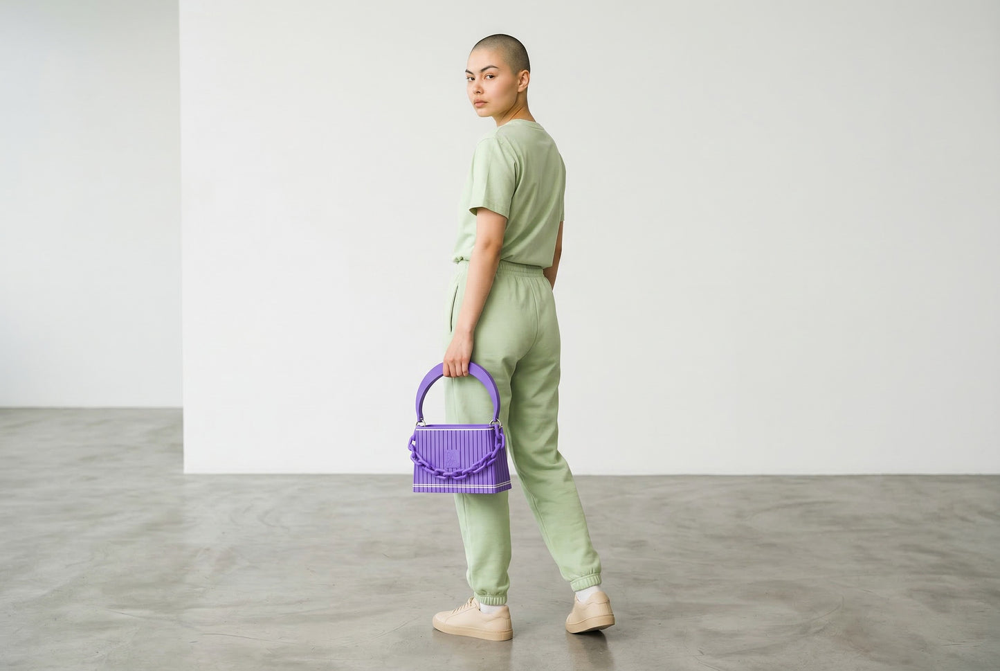 Model trägt HAKO Handtasche in Lila mit Ketten-Detail, moderner Lifestyle-Look im minimalistischen Studio