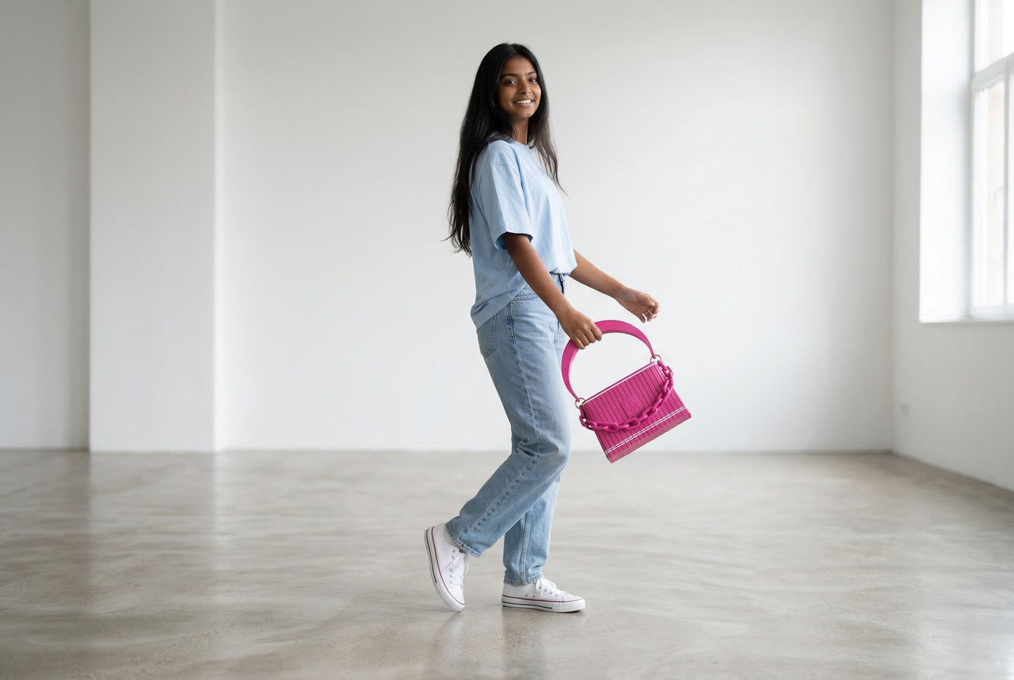 Model trägt HAKO Handtasche in Fuchsia mit Ketten-Detail, lässiger Lifestyle-Look in hellem Studio