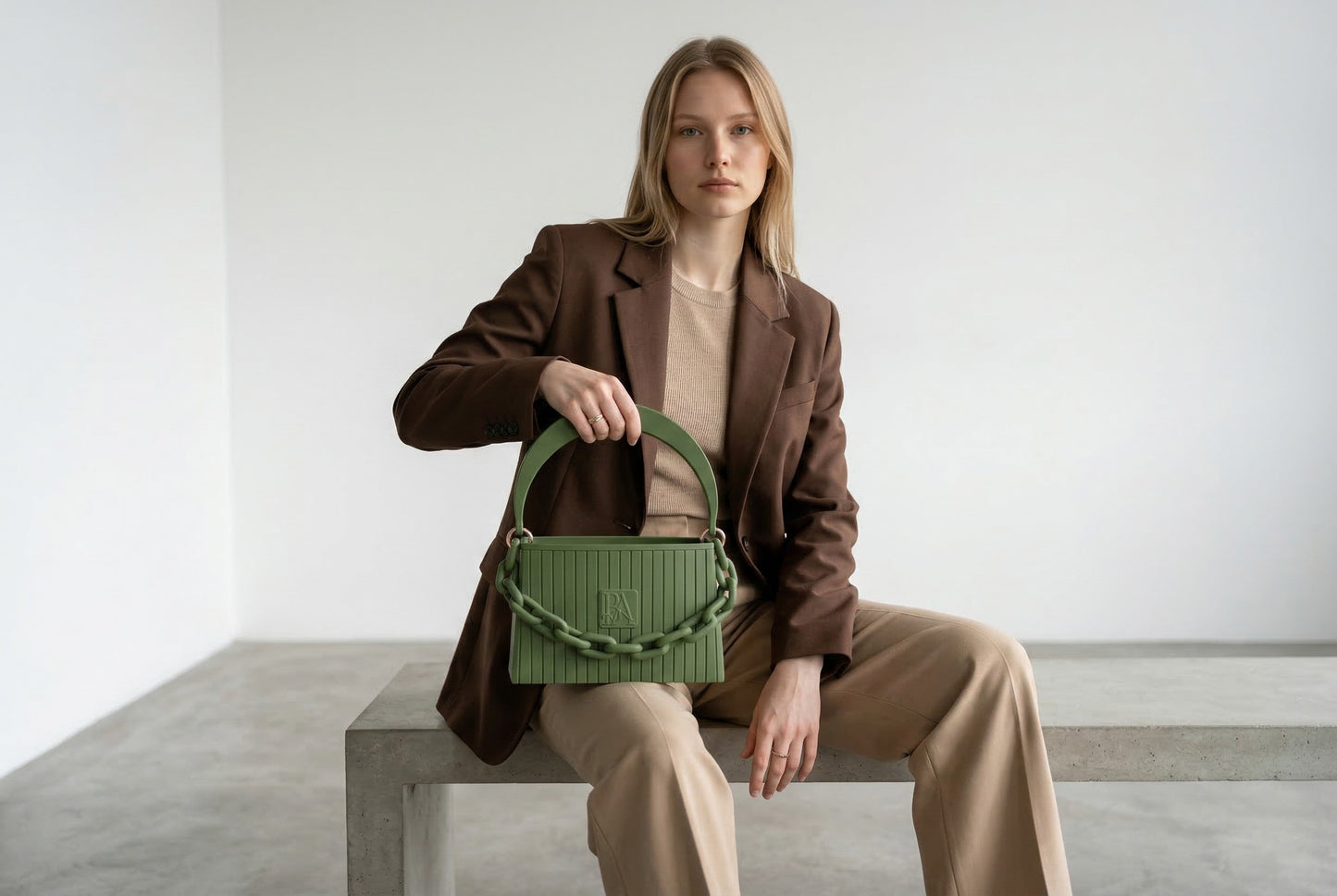 Model trägt HAKO Handtasche in Grün mit Ketten-Detail, eleganter Lifestyle-Look im minimalistischen Studio