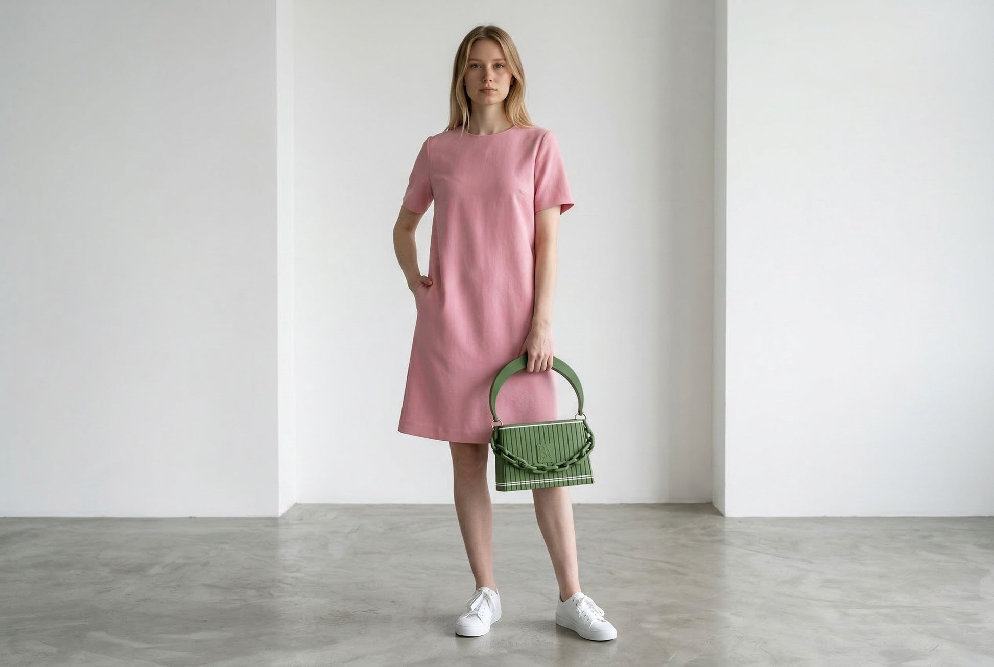 Model trägt HAKO Handtasche in Grün mit Ketten-Detail, moderner Lifestyle-Look im minimalistischen Studio