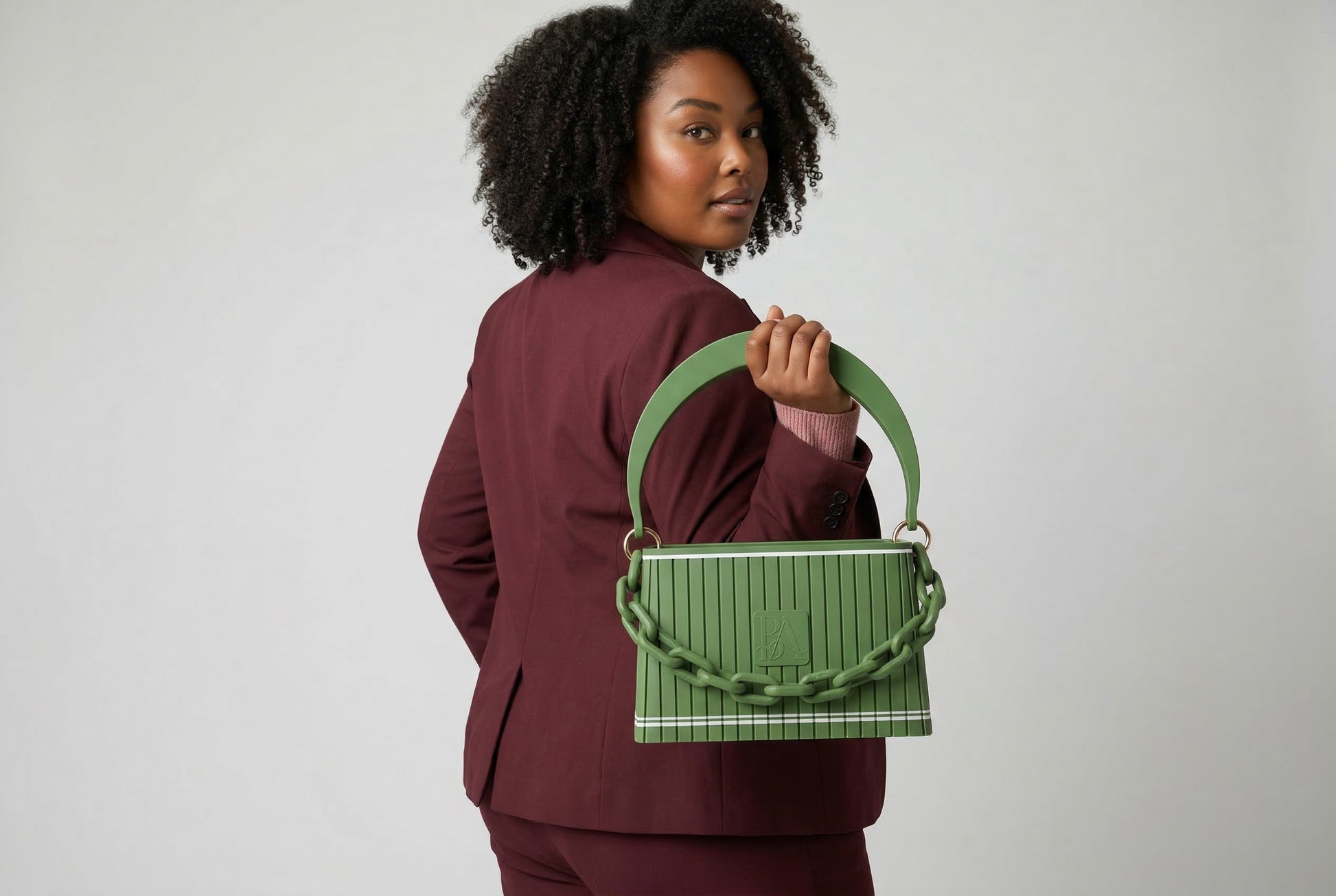 Model trägt HAKO Handtasche in Grün mit Ketten-Detail, moderner Lifestyle-Look im Studio mit Rückansicht