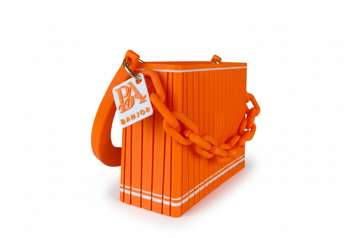 HAKO Handtasche in Orange, Seitenansicht mit strukturierter Oberfläche, Ketten-Detail und BANJOR Anhänger, Designer-Tasche