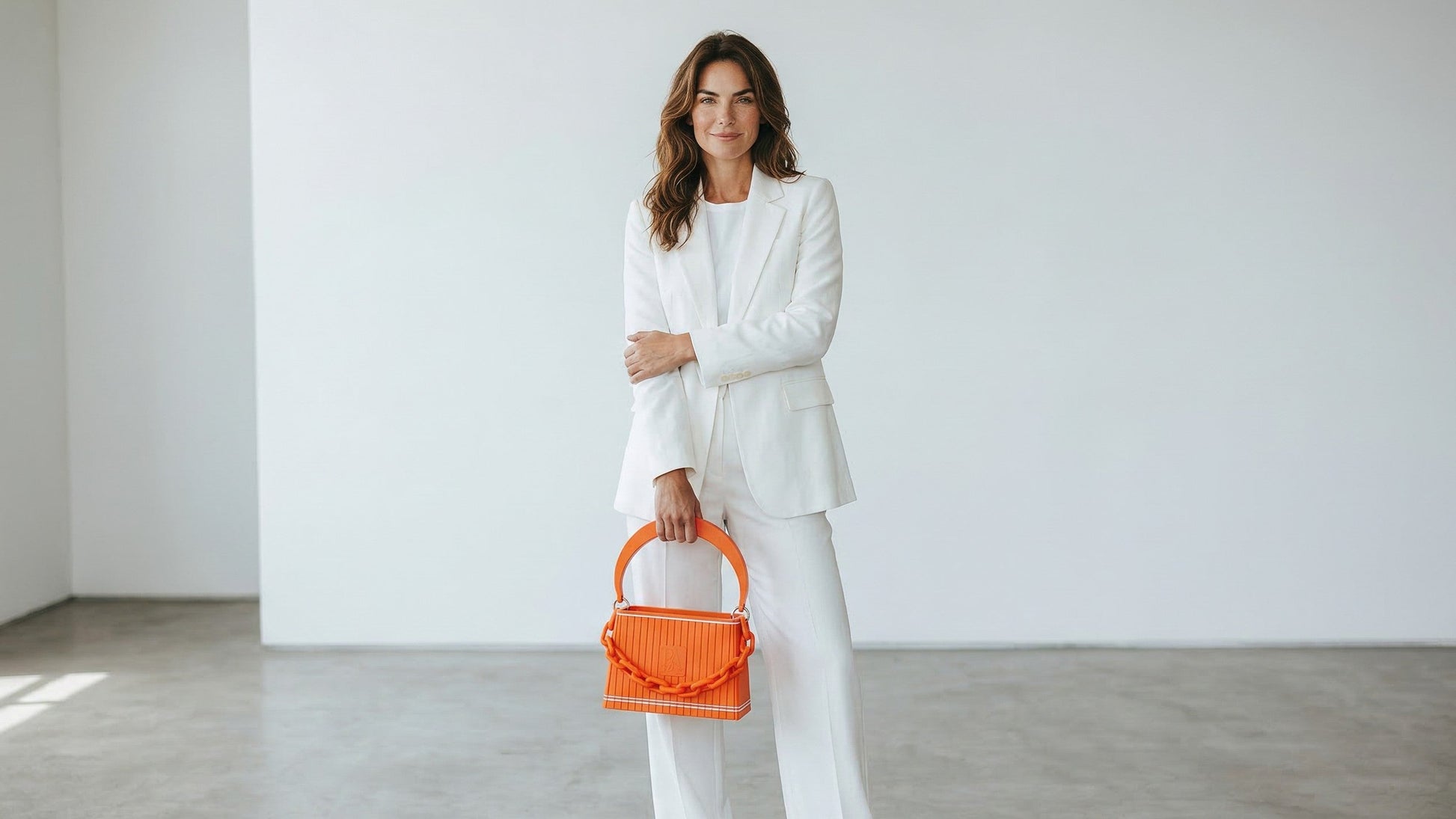 Model trägt HAKO Handtasche in Orange mit Ketten-Detail, Designer-Tasche im eleganten Lifestyle-Look im Studio