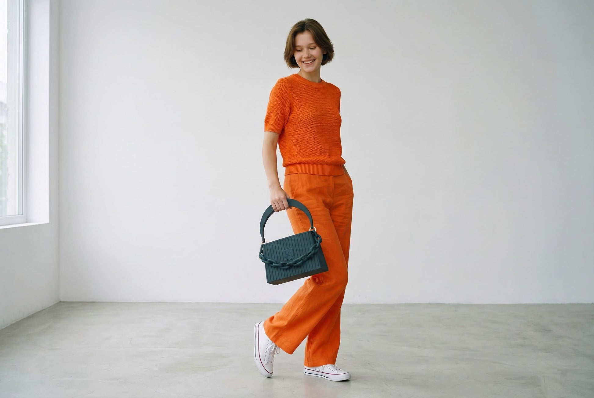 Model trägt HAKO Handtasche in Schwarz mit Ketten-Detail, moderner Lifestyle-Look im minimalistischen Studio