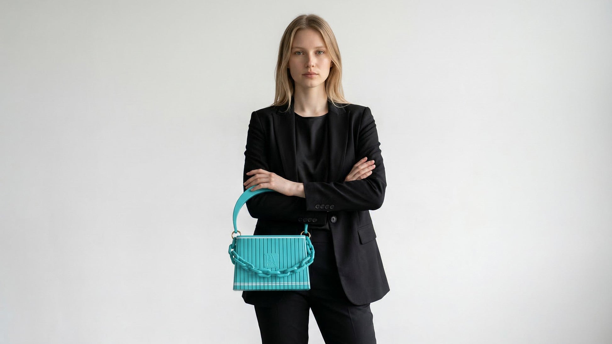 Model trägt HAKO Handtasche in Türkis mit Ketten-Detail, minimalistischer Look im Studio mit neutralem Hintergrund